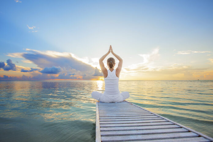 Caucasian woman practicing yoga at seashore